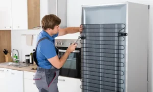 فني يقوم بصيانة ثلاجة منزلية وفحص مكوناتها الداخلية